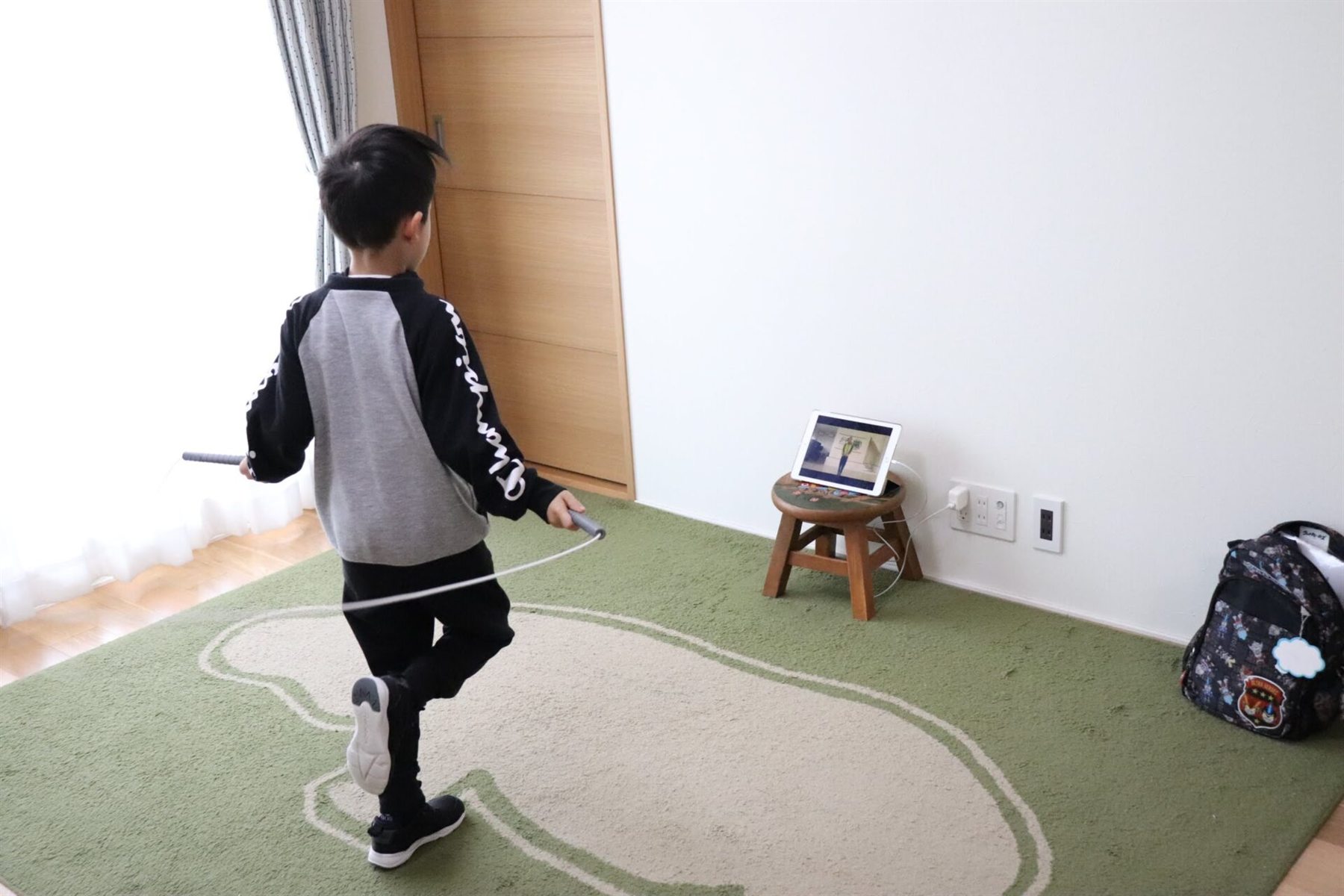 自宅でオンラインレッスンを見ながらなわとびを練習する子ども