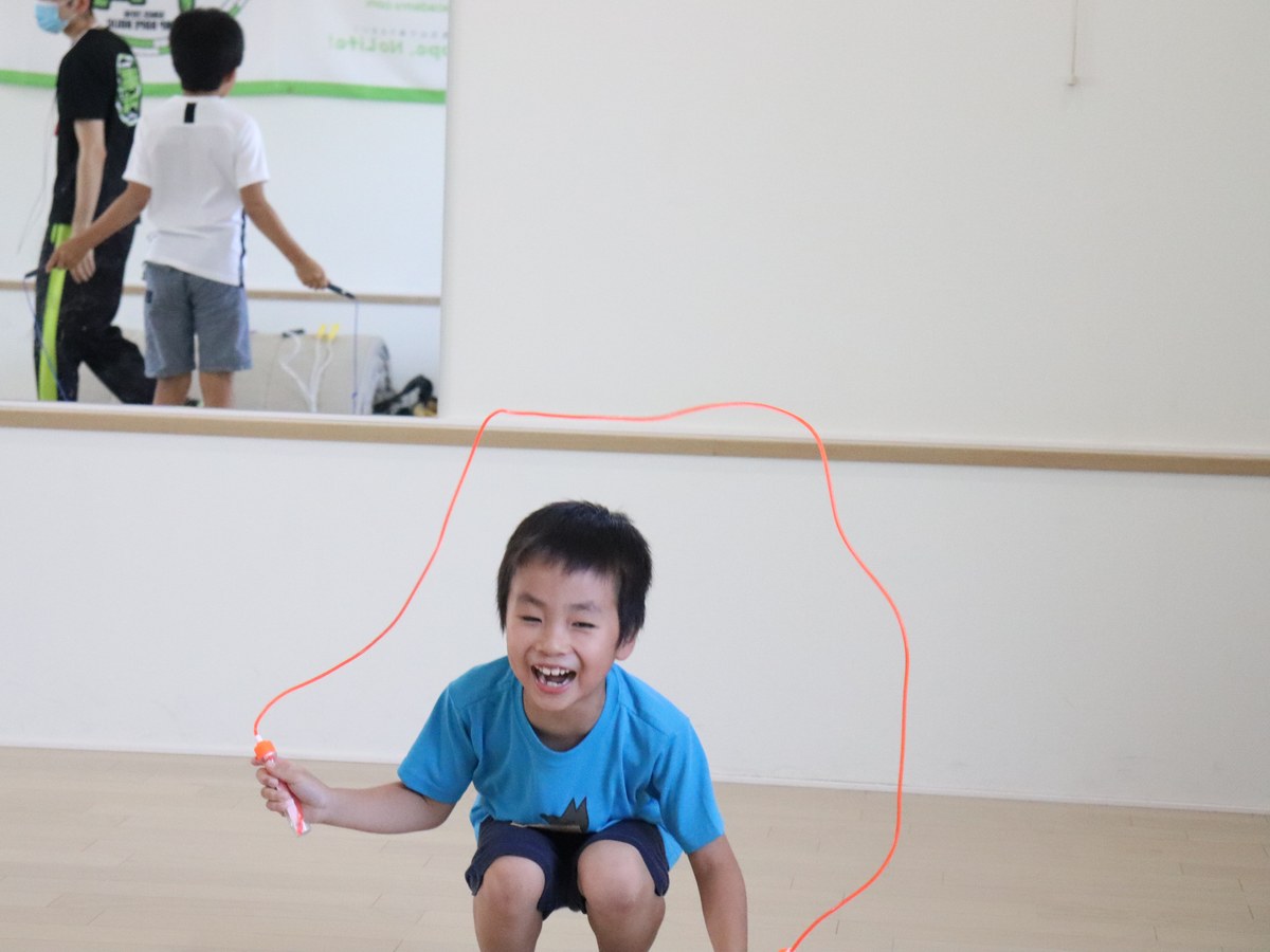 なわとびに挑戦して笑顔を見せる子どものワークショップ風景