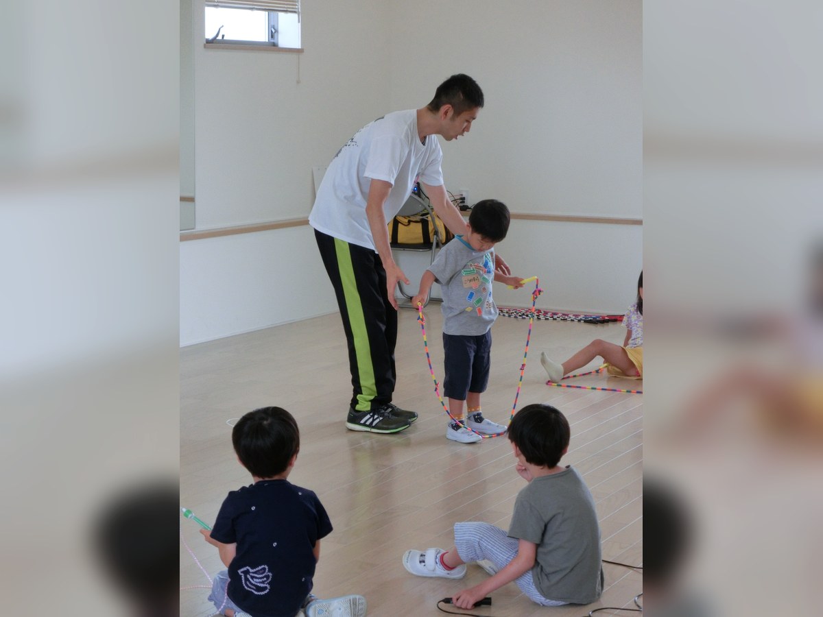 講師が子どもになわとびの持ち方を教える様子