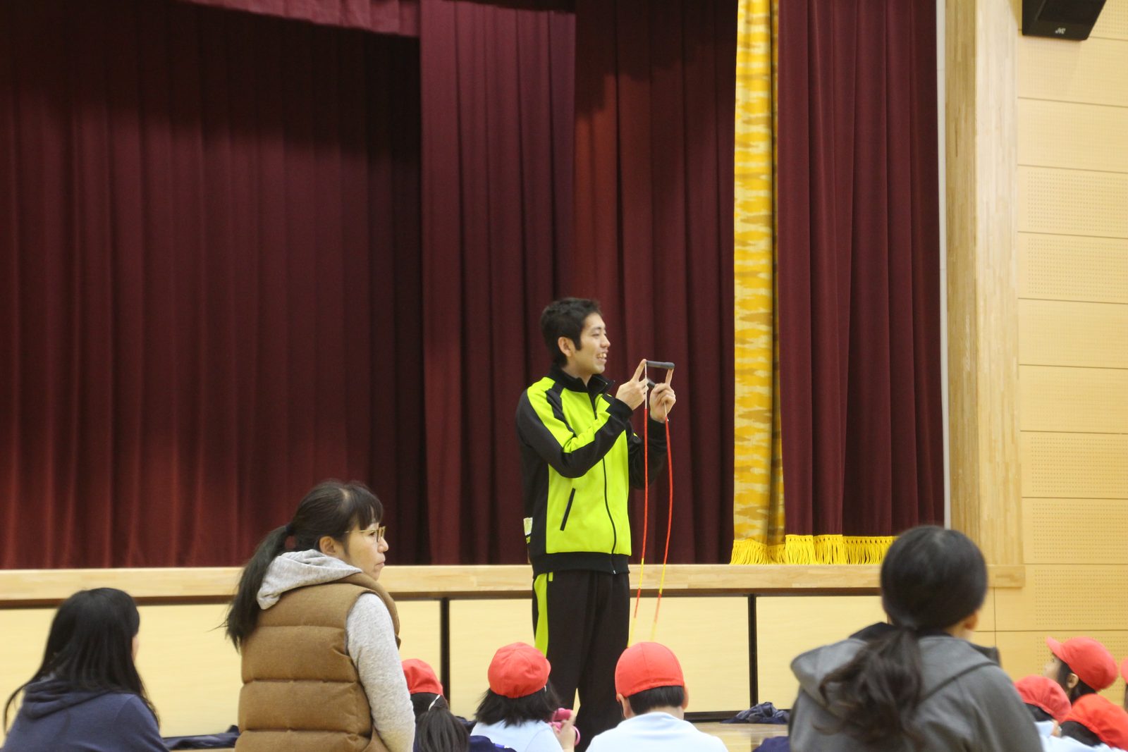 体育館で講師の話を聞く小学生たち