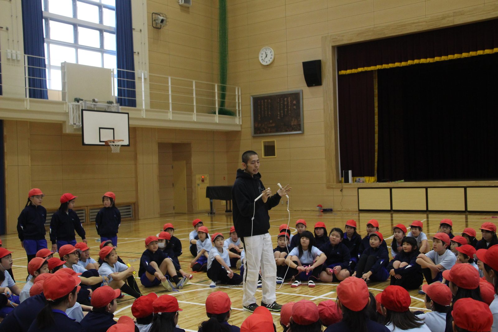 小学校の体育館でなわとび指導を受ける児童たち